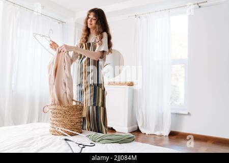 White young woman in apron smiling while doing housework at home Stock Photo