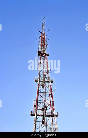 radio, television and mobile antenna tower with jammer aka muffler on blue sky, modern telecommenications diversity Stock Photo