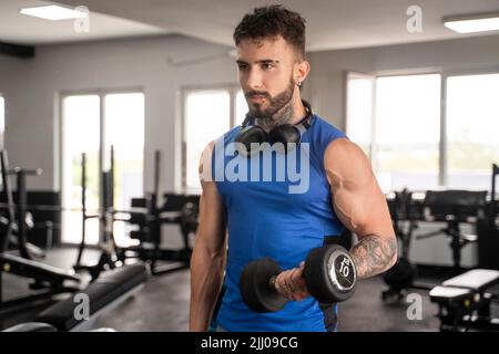 Handsome male with tattoos in his 20s training in the gym Stock Photo