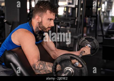 Handsome male with tattoos in his 20s training in the gym Stock Photo