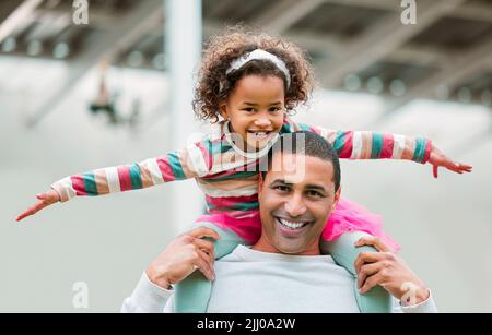 I like it when my dad lifts me this high. a man carrying his daughter on his shoulders. Stock Photo