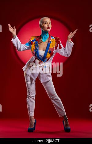 Behold the Queen of the palace. Studio shot of a stylish young woman posing against a red background. Stock Photo