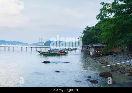 A few fishing boats moored on the bank of the river with houses on stilts. Stock Photo