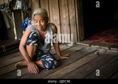 Chini, Malaysia: 19 April 2022 - A close-up of a single indigenous woman sitting on wood Stock Photo