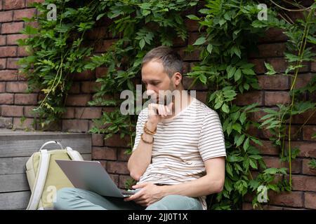 Thoughtful caucasian millennial man wear casual outfit distance working on laptop Stock Photo