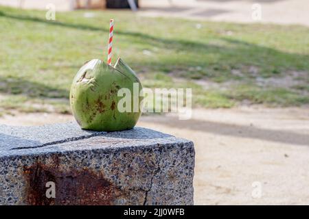 green coconut with a red and white straw on a beach in Rio de Janeiro. Stock Photo