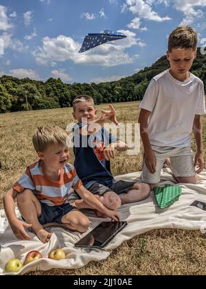Children launch a plane on a picnic, playing on a tablet Stock Photo