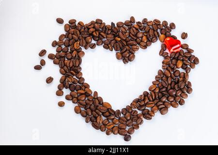Top view. Heart from coffee beans. crystal red heart inside heart made of coffee beans on white background. side view, selective focus, copy space, wi Stock Photo