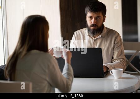 Man and woman working with computer in cafe, informal meeting in coffee shop using laptop, copy space, male freelancer with girlfriend Stock Photo