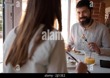 Happy loving couple enjoying breakfast in a cafe. Love, dating, food, lifestyle Stock Photo