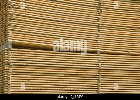 Lots of planks stacked on top of each other in the warehouse. Lumber for further use in construction. Pile of sawn boards Stock Photo
