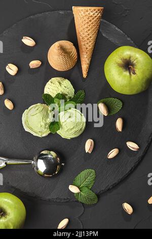 Gourmet pistachio ice cream served on a stone slate over a black background. Stock Photo