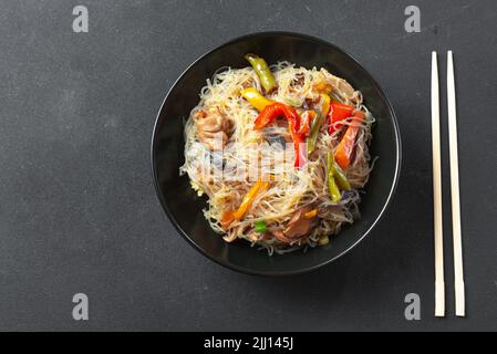 Glass noodle with vegetable in a black bowl on a grey background. Asian food Asian cuisine. Asian or Szechuan noodles. Chinese noodles with vegetables Stock Photo