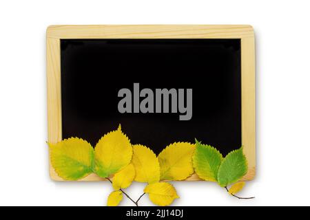 Black chalkboard with yellow and green leaves on white isolated background. Concept back to school, autumn, thanksgiving. Copy space Stock Photo