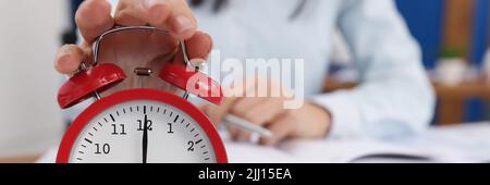 Woman turn off timer on clock at eight oclock in morning, time start work Stock Photo