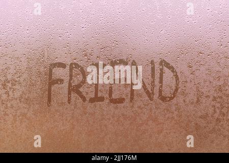 Foggy glass on window with written finger word friend overcast wet window Stock Photo