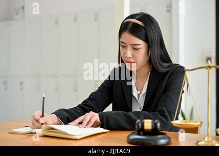 Confident and professional young Asian female lawyer or business law consultant in formal suit making a resignation letter and working at her office d Stock Photo