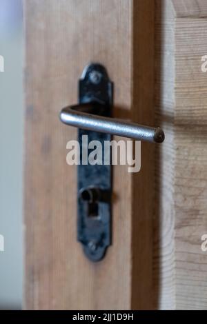 Selective focus shot of iron handle on wooden door. Stock Photo