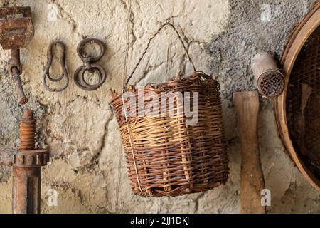 Selective focus shot of old village goods and wooden knitted basket hanging on the wall. Stock Photo