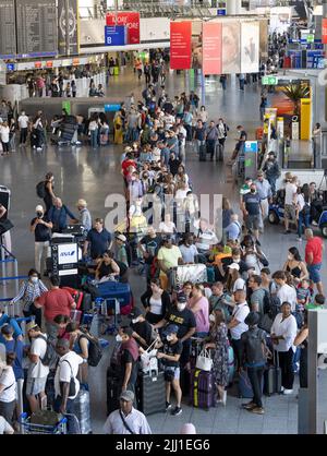 22 July 2022, Hessen, Frankfurt/Main: Thousands of passengers are waiting to check in at the airport's check-in counters. In view of the start of the vacations in several German states, airport operator Fraport is expecting a record rush. Around 200,000 passengers per day are expected on each of the weekends from July 22 to 24, 2022. Photo: Boris Roessler/dpa Stock Photo
