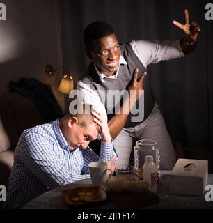 Male friends watching football match on tv and having fun Stock Photo
