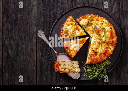 Cauliflower Cake with Pecorino Romano cheese, Basil and spices sliced on black platter on dark wooden table with a slice on cake shovel, horizontal vi Stock Photo
