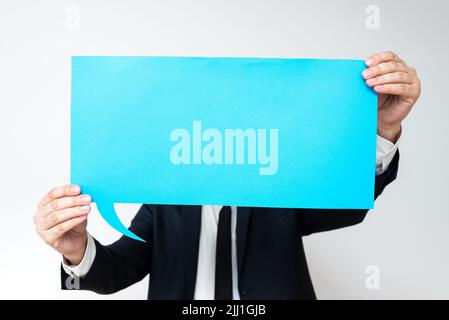Businessman Holding Speech Bubble With Important Messages. Man In Suit Presenting Crutial Informations On Dialogue Balloon. Gentleman Showing Recent Stock Photo
