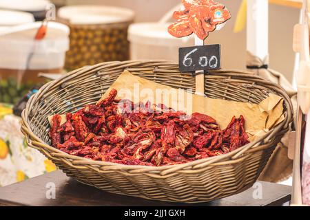 Sun-dried red tomatoes in a wicker basket with price in a street food market in Bari, close up. Ripe tomatoes lose most of their water Stock Photo