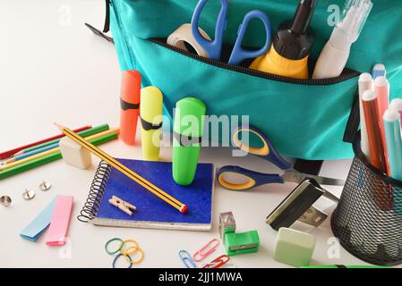 School supplies and blue backpack on white table. Elevated view. Horizontal composition. Stock Photo