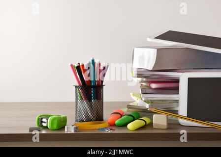 School supplies, books, notebooks and electronic tablets on wood table and white isolated background. Front view Stock Photo