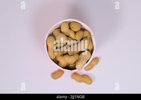 Shelled peanuts in paper cup on a white surface Stock Photo