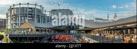 On a warm summers evening in July, people enjoy the selection of open air street cafes and restaurants at Coal Drops Yard on the Regent's Canal at Kin Stock Photo