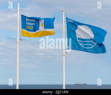 Flag poles on the sea front display Whitley Bay, North Tyneside, UK beach's Seaside Award and Blue Flag for 2022. Stock Photo