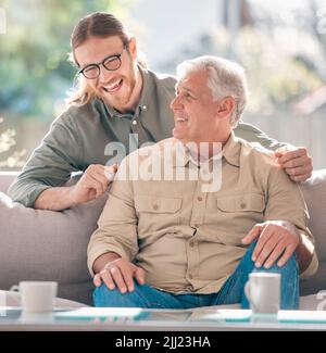 Happy son, happy father. a young man relaxing with his father on the sofa at home. Stock Photo