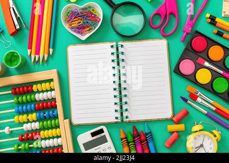 Back to school background. Open notebook on green color office supplies and stationery flat lay, top view. Blank empty paper, copy space Stock Photo