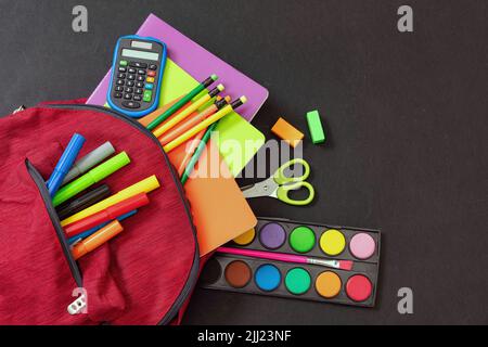 Back to school. School supplies and a red student backpack isolated on black color background, top view, copy space. Stock Photo