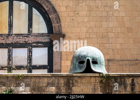 Ancient helmet on wall in front of window of old building in Naples, Italy Stock Photo