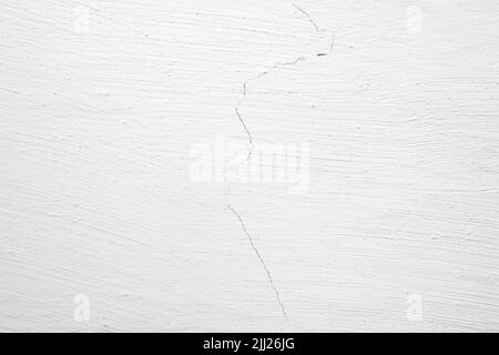 The background is in the form of a section of white wall in a village house. Plastered wall and whitewashed with chalk. Cracked plaster on the wall. Stock Photo