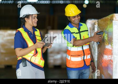 Asian couple warehouse workers checking shipment status on digital tablet computer prepare for delivery to customer. Employees teamwork. Stock Photo