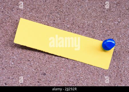 Yellow stick note and blue pinned to a cork notice board. Copy space. Stock Photo