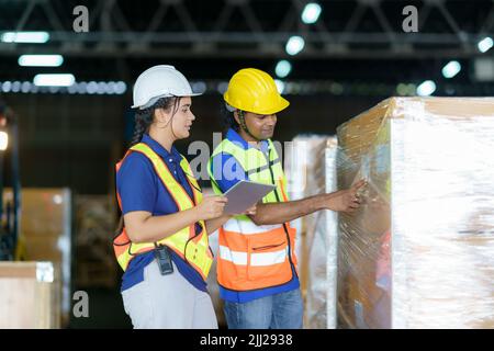 Asian couple warehouse workers checking shipment status on digital tablet computer prepare for delivery to customer. Employees teamwork. Stock Photo