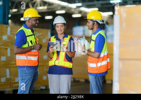 Asian team warehouse workers checking shipment status on digital tablet computer prepare for delivery to customer. Employees teamwork. Stock Photo
