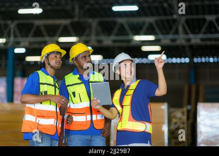 Asian team warehouse workers checking shipment status on digital tablet computer prepare for delivery to customer. Employees teamwork. Stock Photo