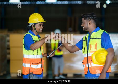 Happy Asian warehouse workers having fun and fist bumping during beginning start work in morning. Stock Photo