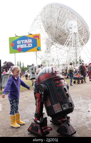 Cheshire, UK. 22nd July, 2022. Young girl meets R3 from Starwars at  Bluedot festival Cheshire infront of the world famous Lovell Telescope .Taking place between 21 – 24 July at UNESCO World Heritage Site, Jodrell Bank, Cheshire United Kingdom, Bluedot is a three day festival of discovery that is a mix of artists, speakers, scientists and performers into an event unlike any on earth. This year’s event headlined by Groove Armada (Friday), Metronomy (Saturday), Mogwai (Saturday) with Björk headlining the Sunday evening with an iconic performance with the Hallé Orchestra. The impressive bill also Stock Photo