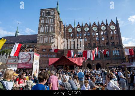 Pomerania, Germany. 22nd July, 2022. 22 July 2022, Mecklenburg-Western Pomerania, Stralsund: Tourists visit the historical market of the Wallenstein Days in front of the Stralsund City Hall. Until July 24, 2021, the people of Stralsund will celebrate the victory over the imperial troops under General Albrecht von Wallenstein almost 400 years ago, on July 24, 1628. The festivities also include a historical market. According to its own information, the folk festival is one of the largest in northern Germany. Photo: Stefan Sauer/dpa/ZB Credit: dpa picture alliance/Alamy Live News Stock Photo