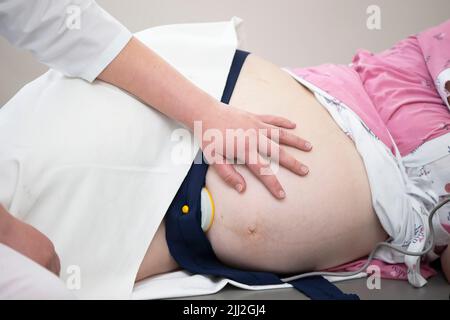 A pregnant woman visits a gynecologist in the field of medicine or medicine for a pregnancy consultant. The doctor examines the belly of a pregnant wo Stock Photo