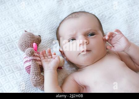 newborn baby laying on bed with his own toy bear Stock Photo