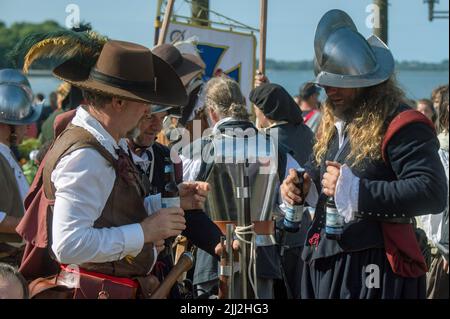 Pomerania, Germany. 22nd July, 2022. 22 July 2022, Mecklenburg-Western Pomerania, Stralsund: Participants wear historical costumes and weapons and hold beer bottles in their hands during the Wallenstein Days. Until July 24, 2021, the people of Stralsund will celebrate the victory over the imperial troops under General Albrecht von Wallenstein almost 400 years ago, on July 24, 1628. The festivities also include a historical market. According to its own information, the folk festival is one of the largest in northern Germany. Photo: Stefan Sauer/dpa Credit: dpa picture alliance/Alamy Live News Stock Photo