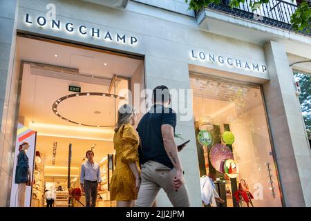 Pedestrians walk past the French luxury fashion brand Louis